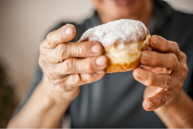 Older woman's hands holding a donut